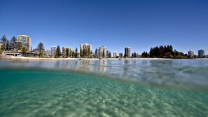 Un paysage urbain côtier avec de hauts immeubles, une plage et une eau turquoise cristalline.