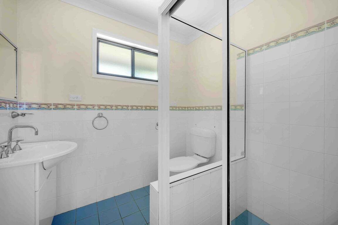 A bathroom with a sink, toilet, and a window.