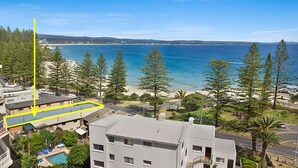 Un quartier résidentiel situé sur la côte, offrant une vue sur la mer, doté d’une piscine et traversé par une route dont le marquage au sol est une ligne jaune.