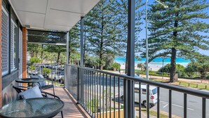 Un balcon avec coin salon extérieur donnant sur une plage et un espace de stationnement.