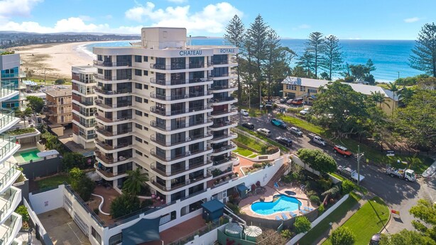 Un hotel de varios pisos con balcones, piscina y vistas a la playa y al océano.
