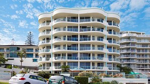 Een meerlaags hotel met balkons, een heldere lucht en een bord waarop staat 'Bay Resort'.