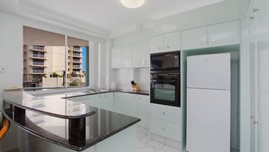 Een moderne keuken met witte kasten, een zwart aanrechtblad en een inbouwoven.