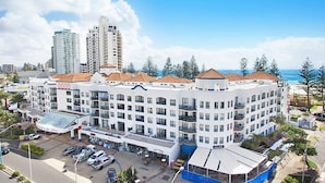 A multi-story hotel with a central courtyard, outdoor seating, and a view of the ocean. - Calypso Plaza Resort Unit 417 Two bedroom unit in resort style complex central Coolangatta (Coolangatta)