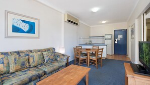 En kompakt opholdsstue med sofa, spisebord og fjernsyn.