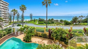 Un resort con piscina, palmeras y vista al océano.