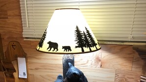 A lamp with a bear and tree design, a wooden table, and a wooden wall. - HOT TUB COTTAGE near Cave Run Lake, Kentucky, Red River Gorge,Morehead Kentucky (Wellington)