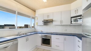 A modern kitchen with white cabinets, a Bosch dishwasher, a stainless steel oven, and a window with a city view. - Kooringal Unit 20 Located right on Greenmount beach with ocean views (Coolangatta)