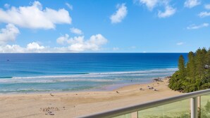 Una playa con aguas azules cristalinas, orilla arenosa y vistas al océano.