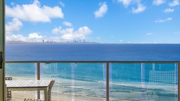 A balcony with a view of the ocean and a distant city skyline.