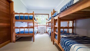 Une chambre avec un lit superposé, une fenêtre et une petite commode.