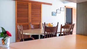 Un coin repas avec une table et des chaises en bois, un vase rempli de fleurs et un mur orné de tableaux encadrés.