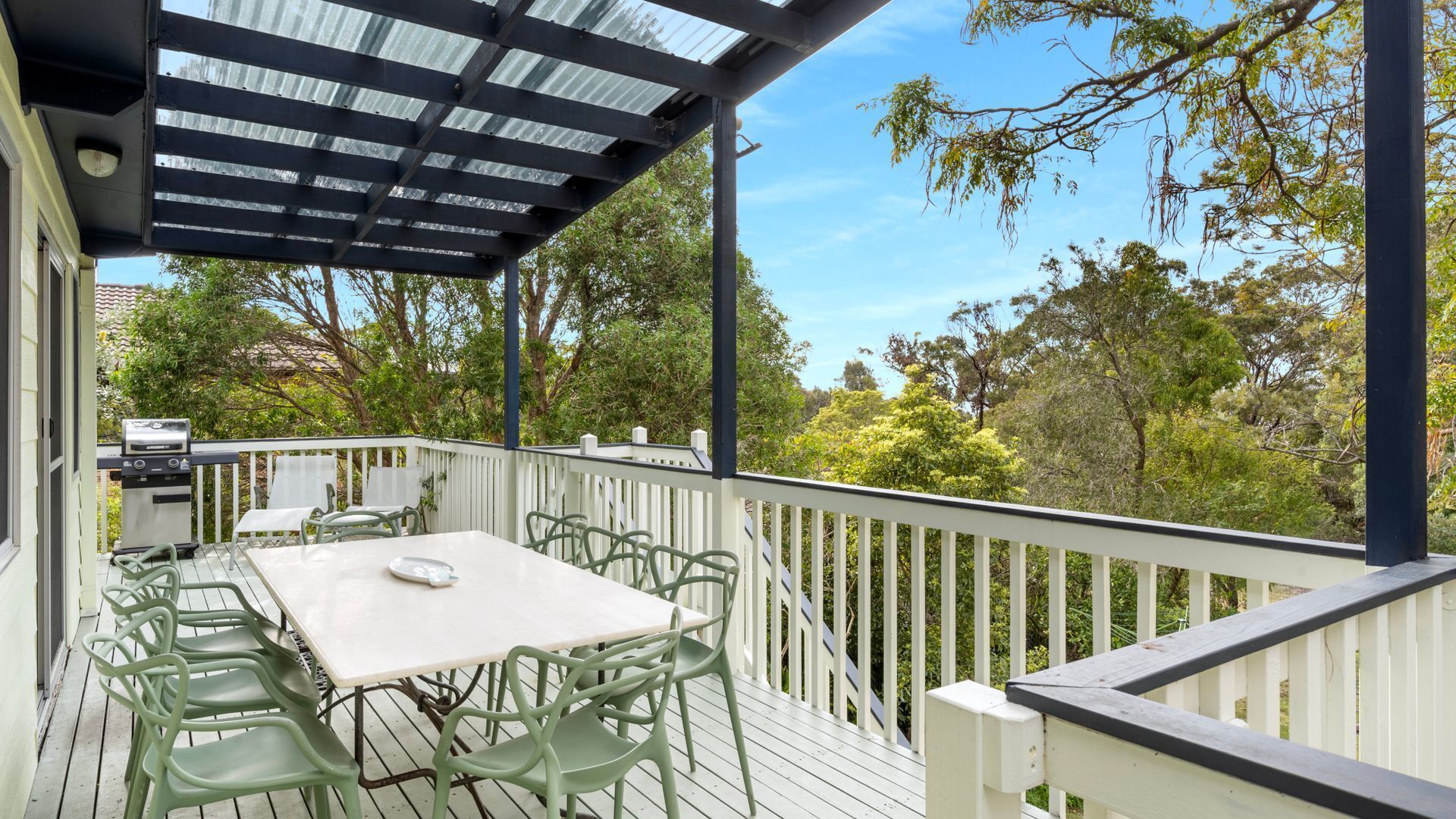 An outdoor deck with a covered area, a table, and chairs.