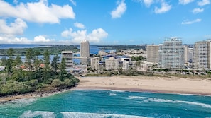 Un paysage urbain côtier avec de hauts immeubles, une plage et une eau bleue et limpide.