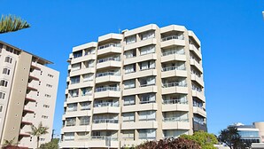 Een meerlaags woongebouw met balkons, grote ramen en een helderblauwe lucht.