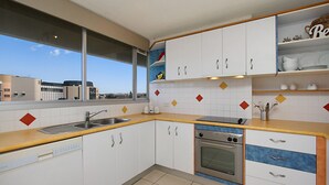 Een moderne keuken met witte kastjes, een roestvrijstalen spoelbak en een ingebouwde oven.