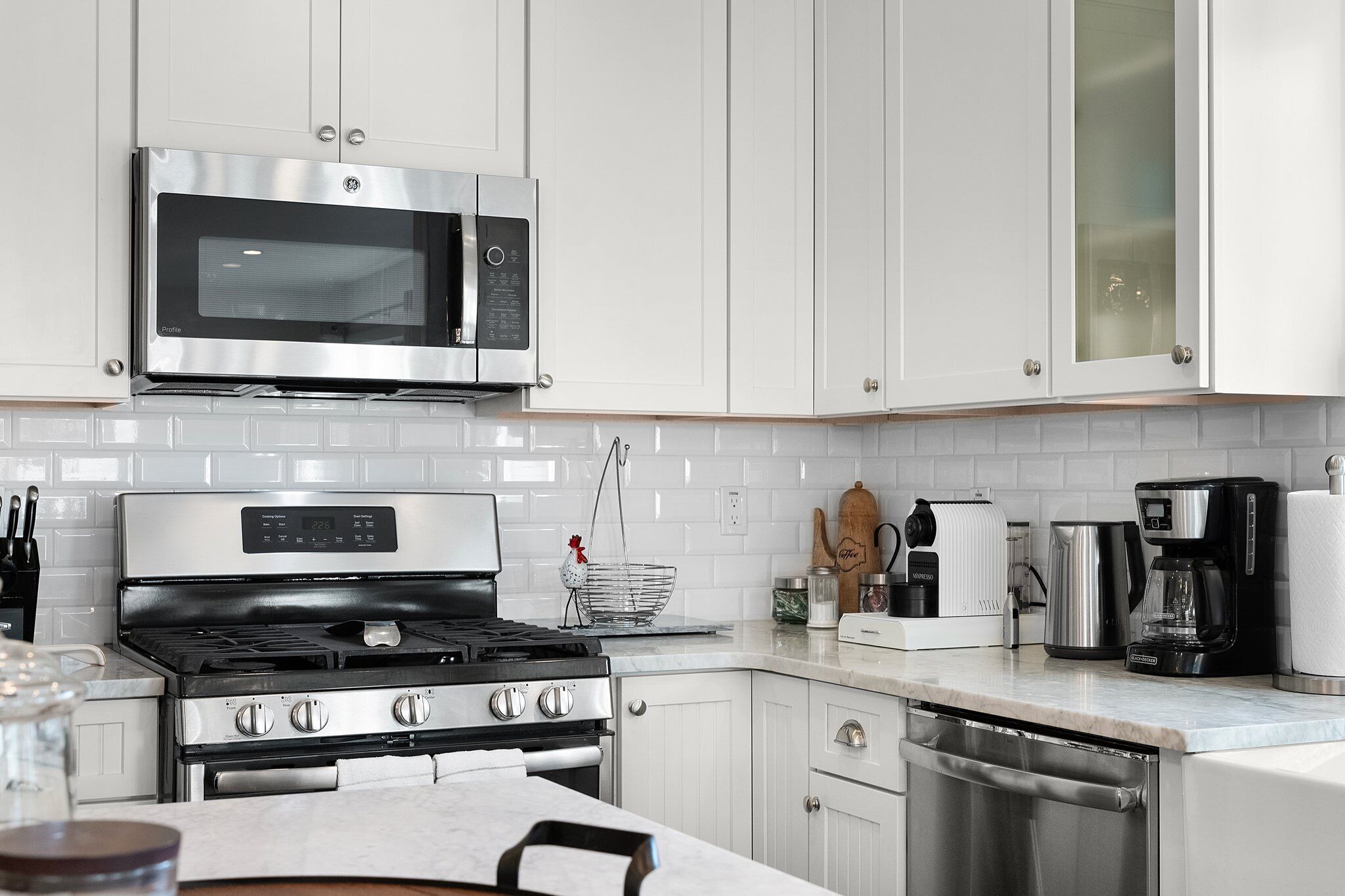 Una cocina moderna con armarios blancos, electrodomésticos de acero inoxidable y encimera de mármol.