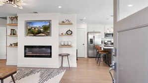 A modern living room with a fireplace, TV, and shelves with decorative items. - Urban Elegance in Wine Country: Unwind Just Steps from Healdsburg Plaza! (Healdsburg)