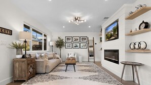 A modern living room with a sofa, a coffee table, a fireplace, and a television. - Urban Elegance in Wine Country: Unwind Just Steps from Healdsburg Plaza! (Healdsburg)