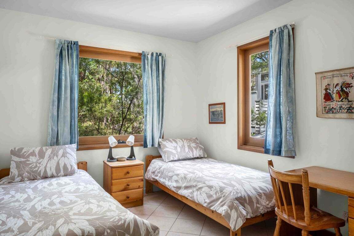 A bedroom with two single beds, a wooden desk, and a chair.