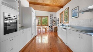 Une cuisine moderne avec des meubles blancs, un plancher en bois et un plafond en bois.