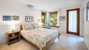 Une chambre à coucher avec un lit, des tables de chevet, une chaise et une fenêtre avec des rideaux.
