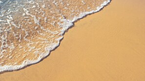 A sandy beach with gentle waves lapping at the shore.