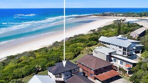Un quartier résidentiel situé sur la côte, avec des maisons à proximité de la plage, caractérisé par un mélange d’architecture moderne et traditionnelle.
