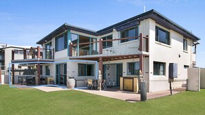 Une maison moderne à deux étages, dotée d’un balcon, d’un espace salon extérieur et d’une statue.