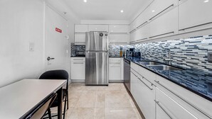 A modern kitchen with white cabinets, a stainless steel refrigerator, and a tiled backsplash. - Apartment Luxury The Tides on the Beach with Ocean View  (Hollywood)