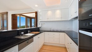 A modern kitchen with white cabinetry, a black countertop, and a built-in oven. - Orion Unit 7 Modern apartment with Wi-Fi included, overlooking Snapper Rocks and Rainbow Bay (Coolangatta)