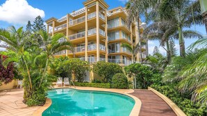 A multi-story hotel with a swimming pool surrounded by lush greenery and palm trees. - Orion Unit 7 Modern apartment with Wi-Fi included, overlooking Snapper Rocks and Rainbow Bay (Coolangatta)