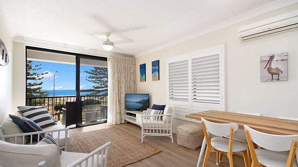 A spacious living area with a balcony overlooking a scenic view, a television, and a dining table with chairs. - Kirra Vista Apartments Unit 18 Kirra Beachfront, easy walk to shops, cafes and clubs with Wi-Fi (Coolangatta)