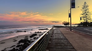 A coastal walkway with a view of the ocean and a sunset. - Kirra Vista Apartments Unit 18 Kirra Beachfront, easy walk to shops, cafes and clubs with Wi-Fi (Coolangatta)