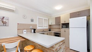 A compact kitchen with a central island, a refrigerator, a microwave, and a coffee maker. - Kirra Vista Apartments Unit 18 Kirra Beachfront, easy walk to shops, cafes and clubs with Wi-Fi (Coolangatta)