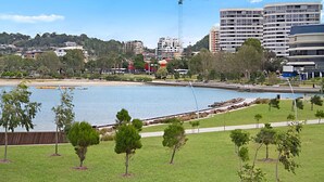 Un paisaje urbano costero con un puerto deportivo, zonas verdes y edificios modernos.