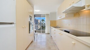 Eine moderne Küche mit weißen Schränken, einem eingebauten Backofen und einem großen Fenster mit Blick auf eine Stadtlandschaft.
