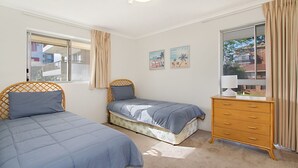 Ein Schlafzimmer mit zwei Betten, einem Schminktisch und einem Fenster mit Vorhängen.