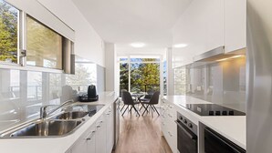 Una cocina moderna con comedor, ventanas amplias y vistas a árboles.
