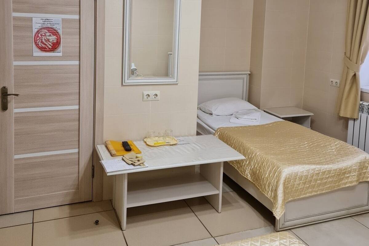 Une chambre à coucher comprenant un lit, une table de chevet, un miroir et une porte avec une pancarte.