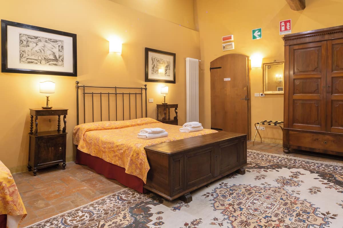 Une chambre d’hôtel avec un lit, une armoire en bois, un radiateur et un tapis à motifs.