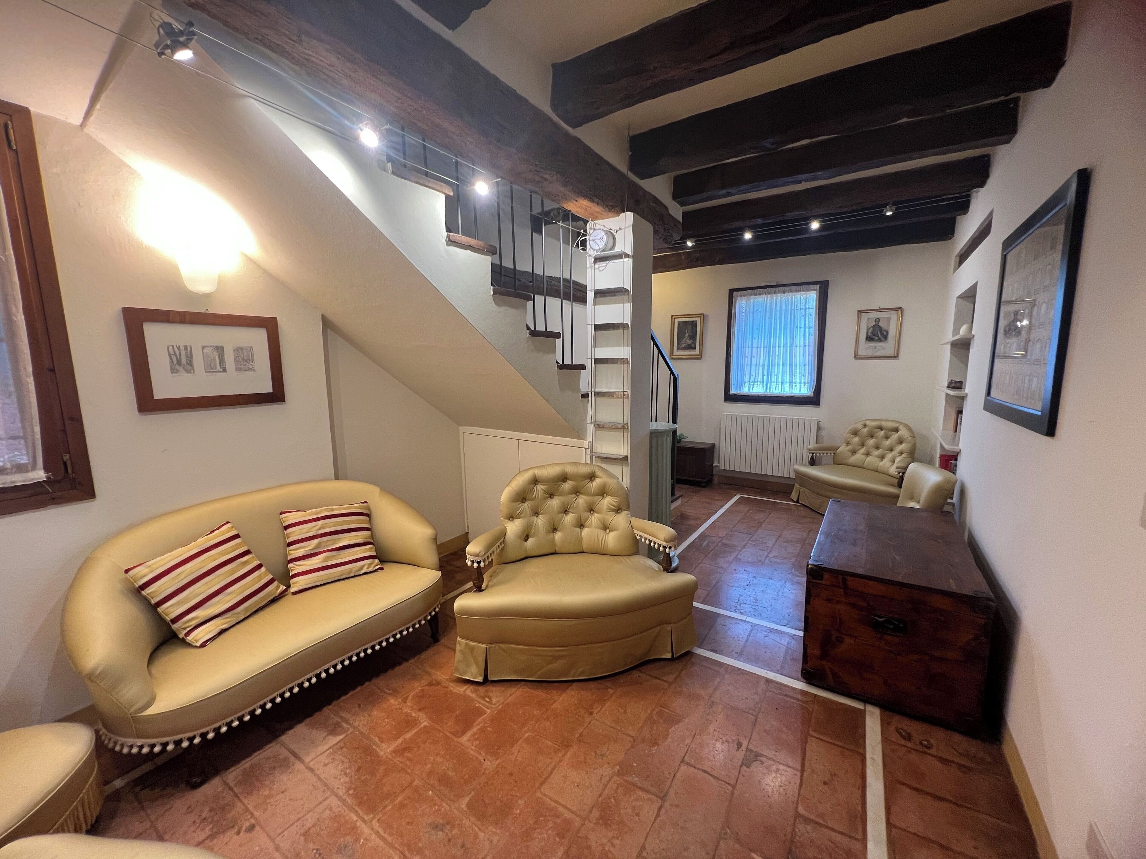 Un'ampia zona giorno con soffitto alto, una scala e una grande finestra.