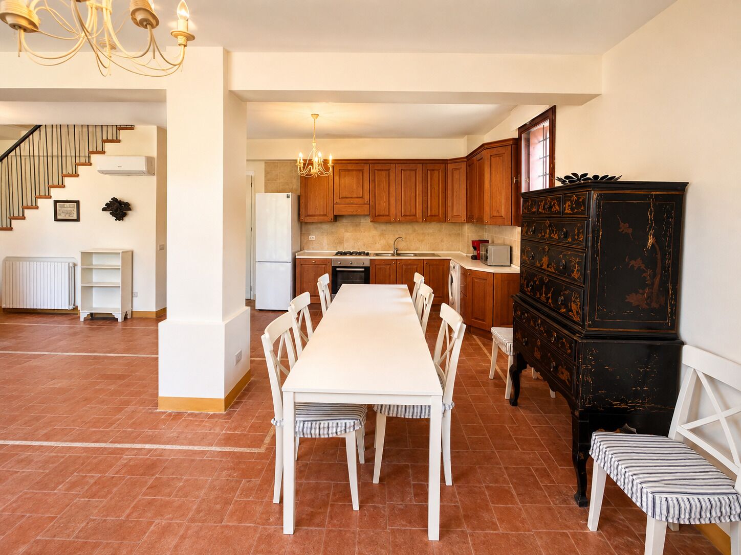 Una cocina moderna con armarios de madera, una mesa de comedor con sillas y un mueble negro con detalles intrincados.