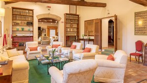 A spacious living area with multiple seating options, a fireplace, and a library filled with books and decorative items. - Borgo Malvasia- Ca' Palazzo (Sasso Marconi)
