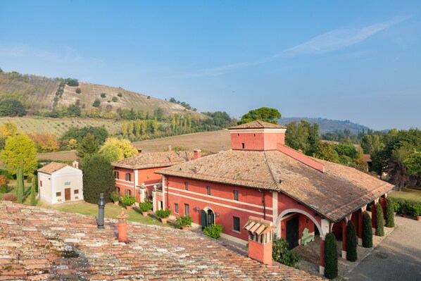 A red-roofed building with a courtyard, surrounded by greenery and hills.