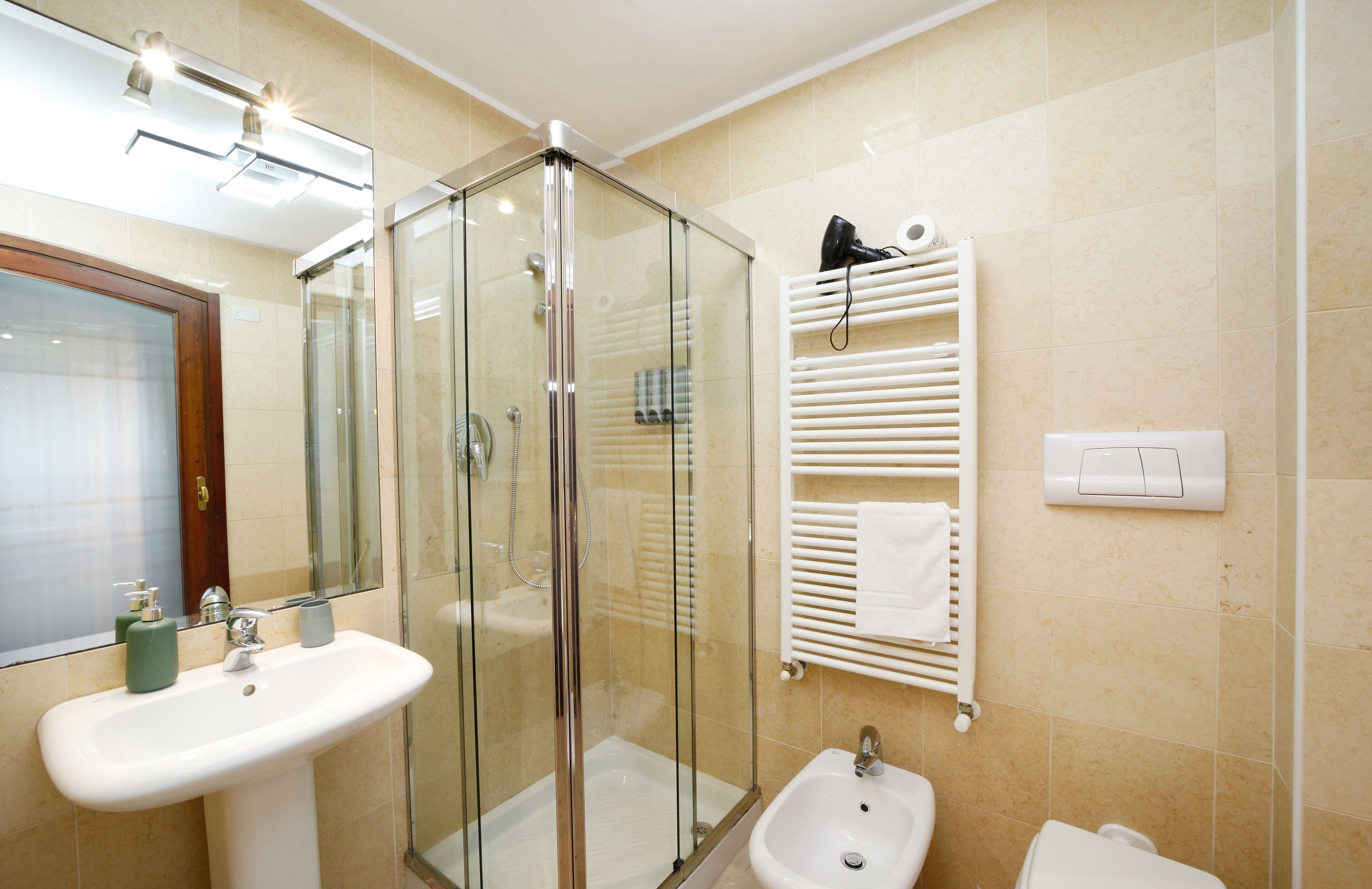 A modern bathroom with a glass-enclosed shower, a sink, and a bidet.