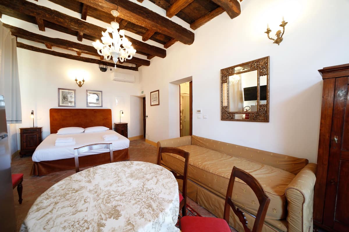 Une chambre à coucher avec un lit, un canapé, une chaise, une table et un miroir.