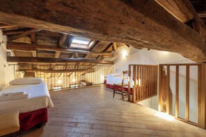 A rustic room with exposed wooden beams, a loft bed, a wooden chair, and a small staircase. - Borgo Malvasia- Ca' Palazzo (Sasso Marconi)