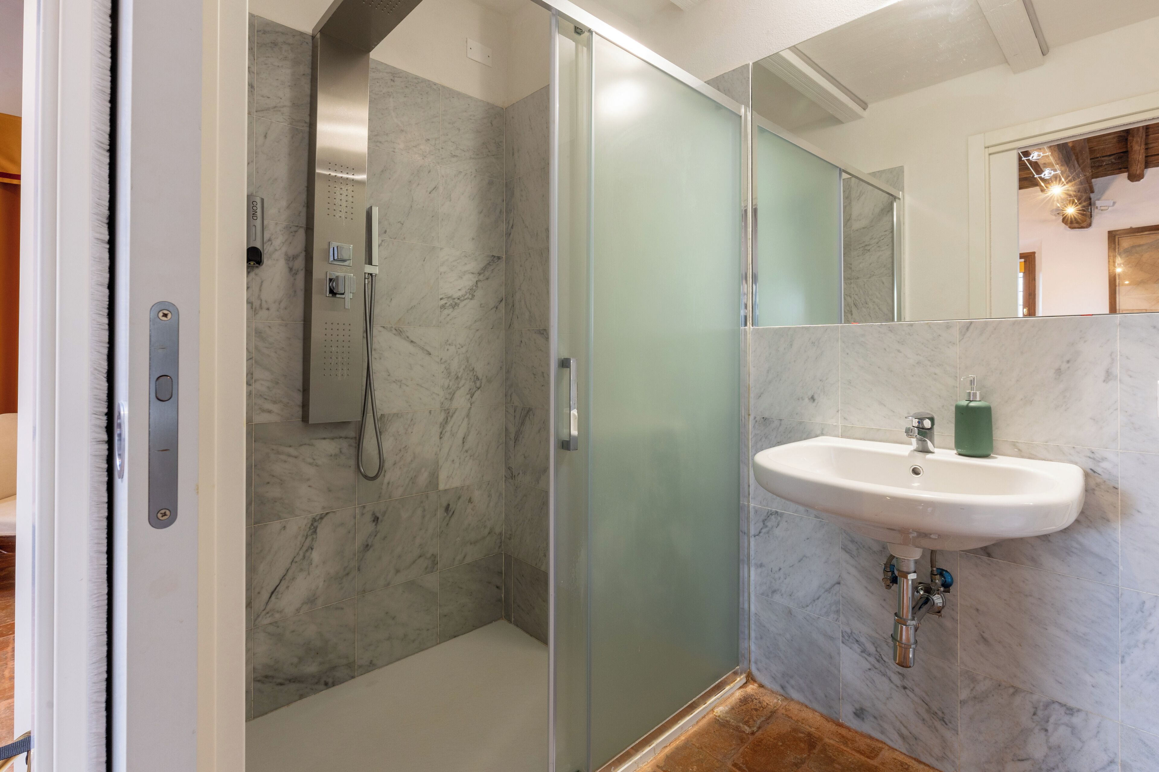 Une salle de bain moderne avec une douche à parois de verre, un lavabo blanc et des carreaux de marbre.