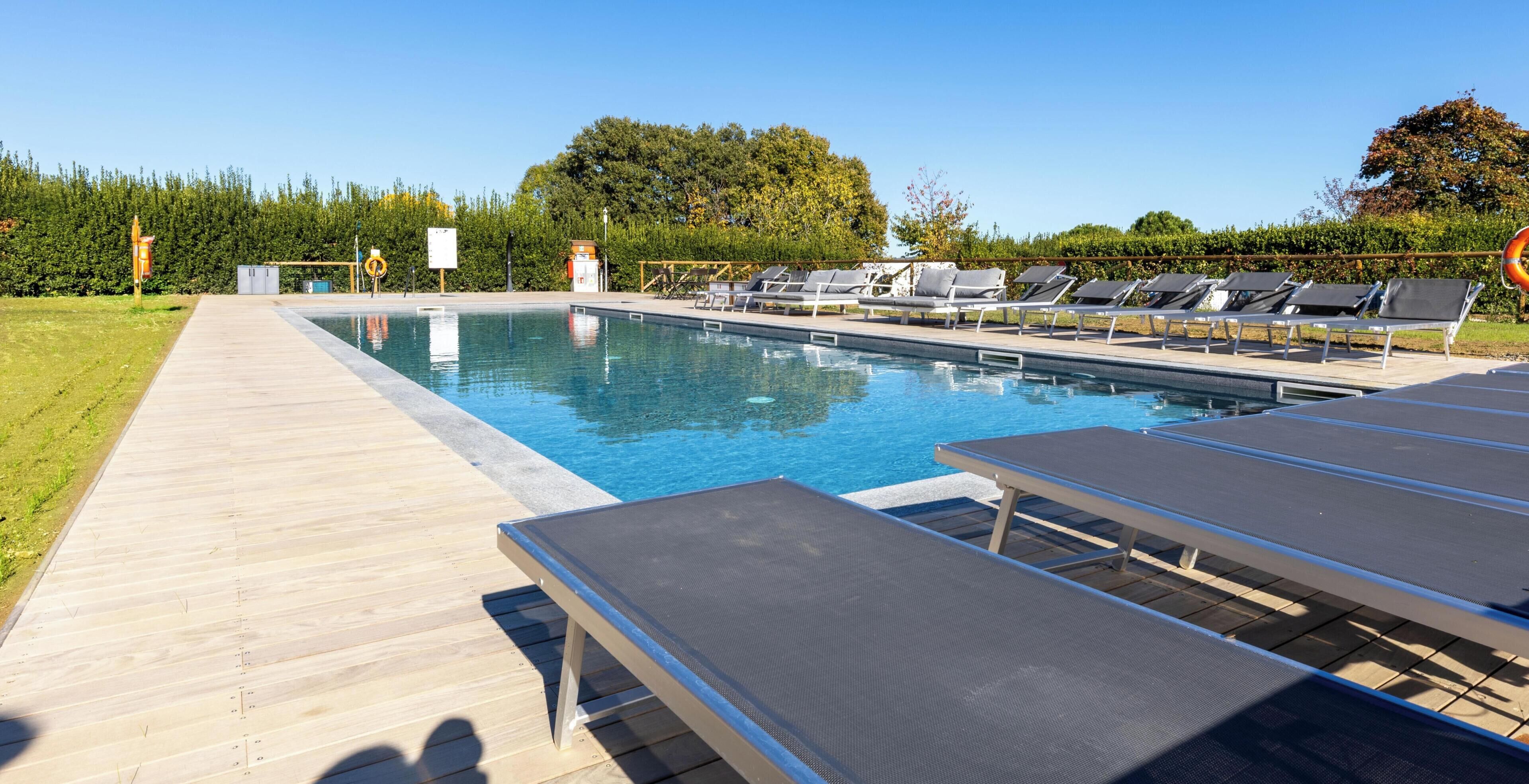 Une piscine avec des chaises longues et une terrasse en bois.